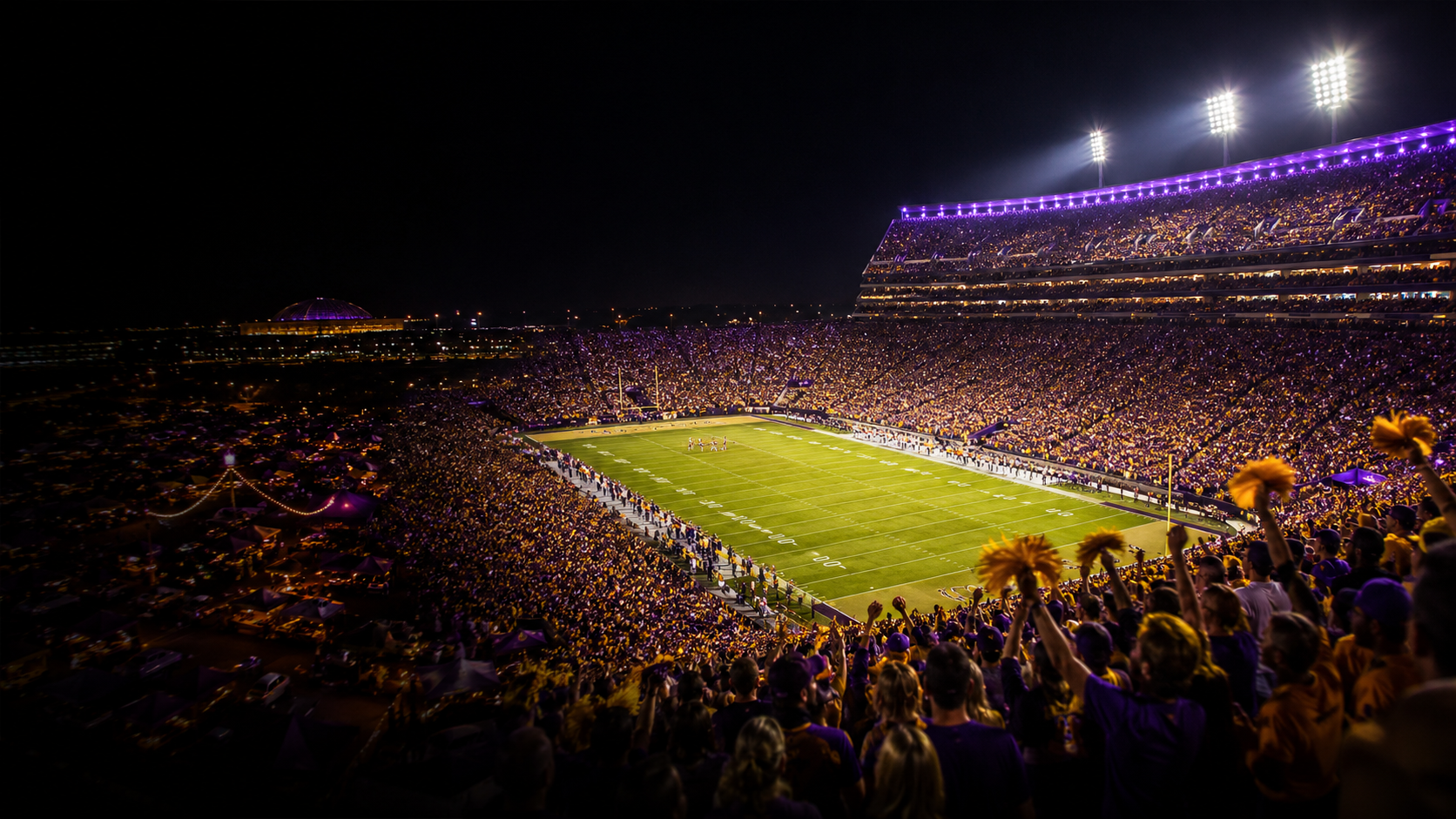 Purple and gold college football stadium on game night